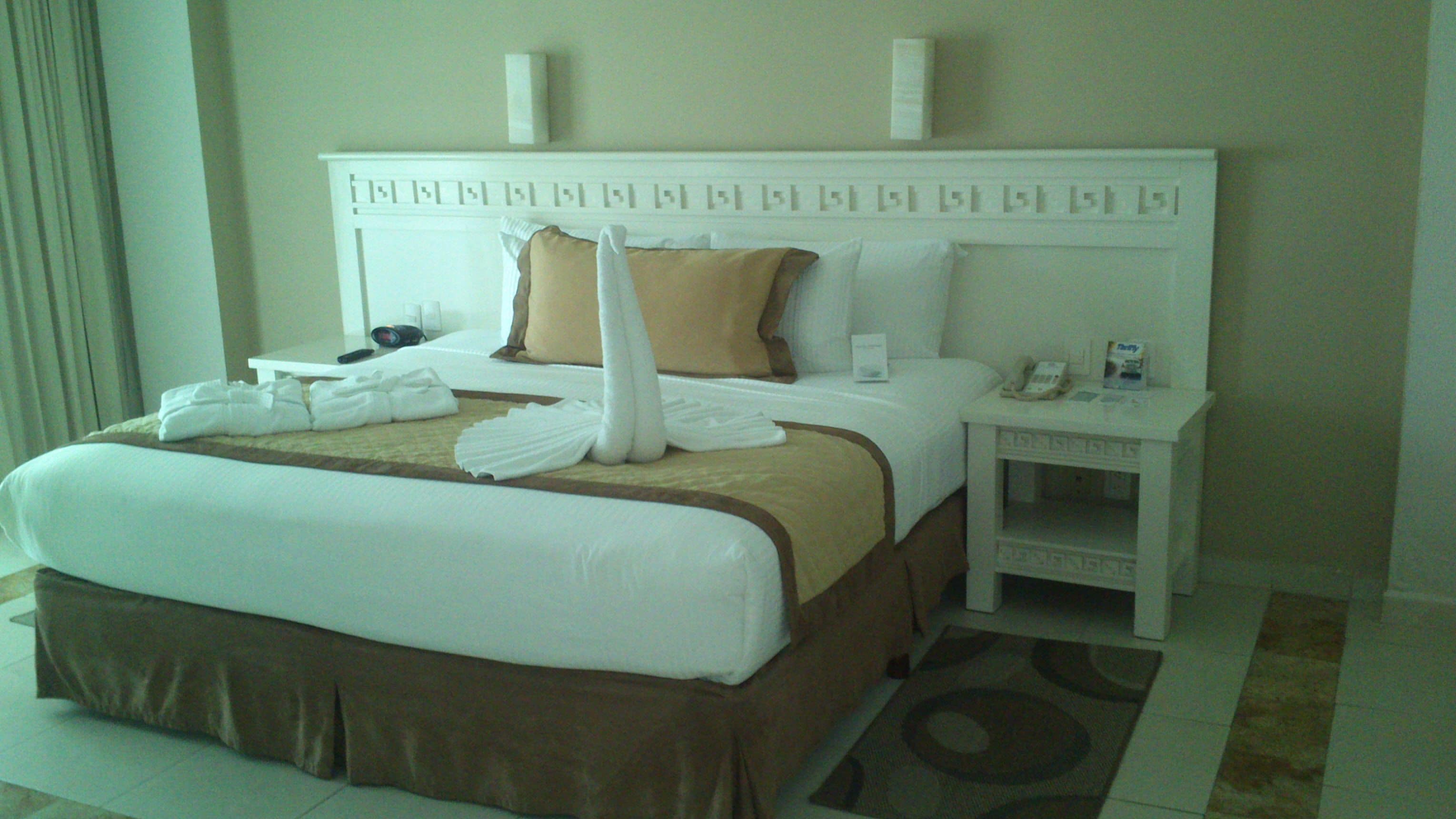 Une chambre d’hôtel avec un grand lit, une table de chevet, un téléphone et une télécommande.