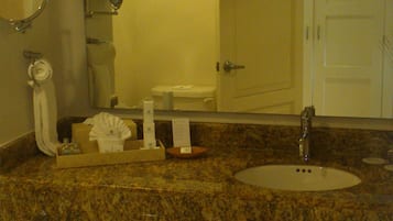 Une salle de bain avec un comptoir en granit, un lavabo, un miroir, un porte-serviettes et une porte.