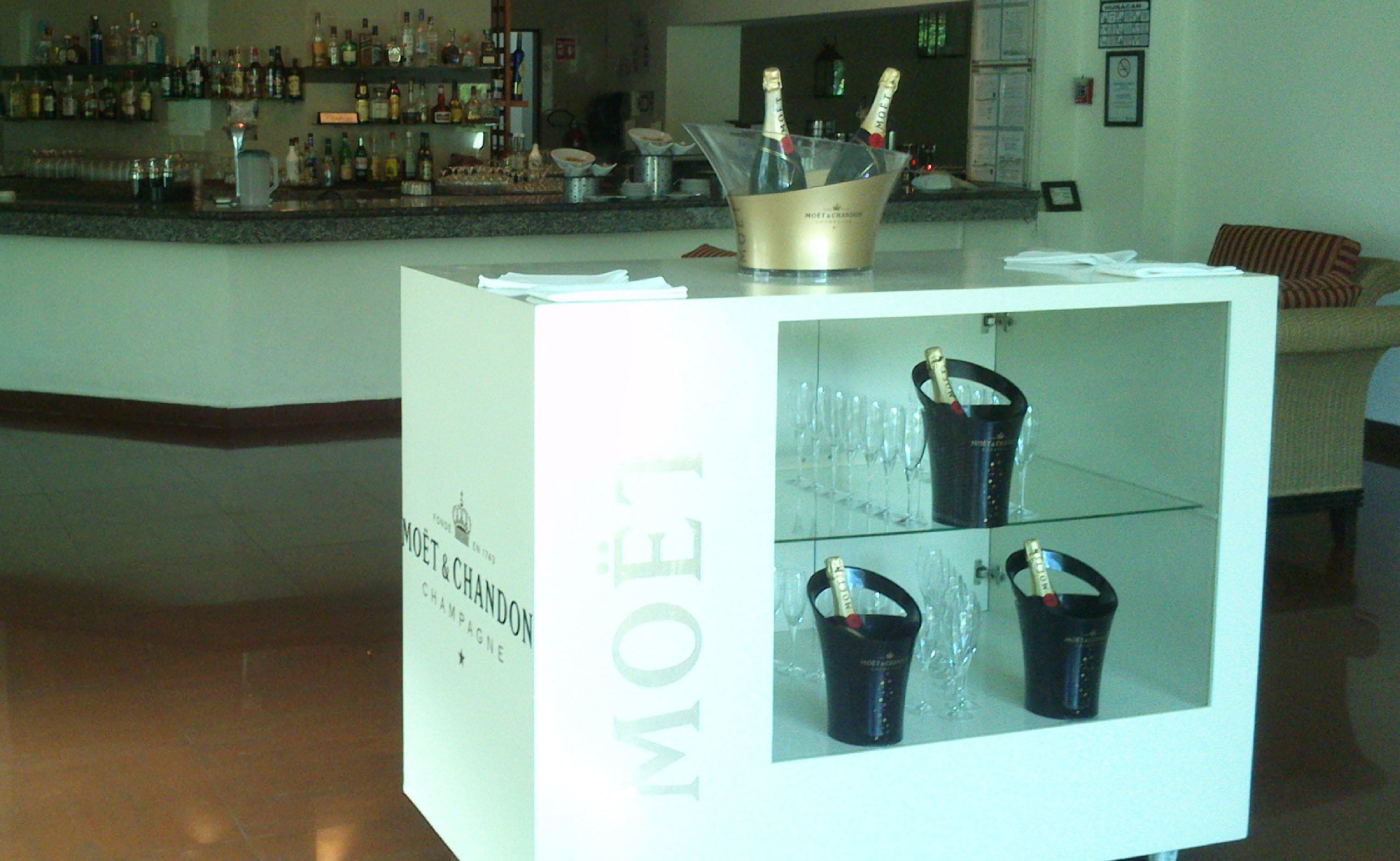 Un área de bar con un frigobar lleno de botellas y vasos.
