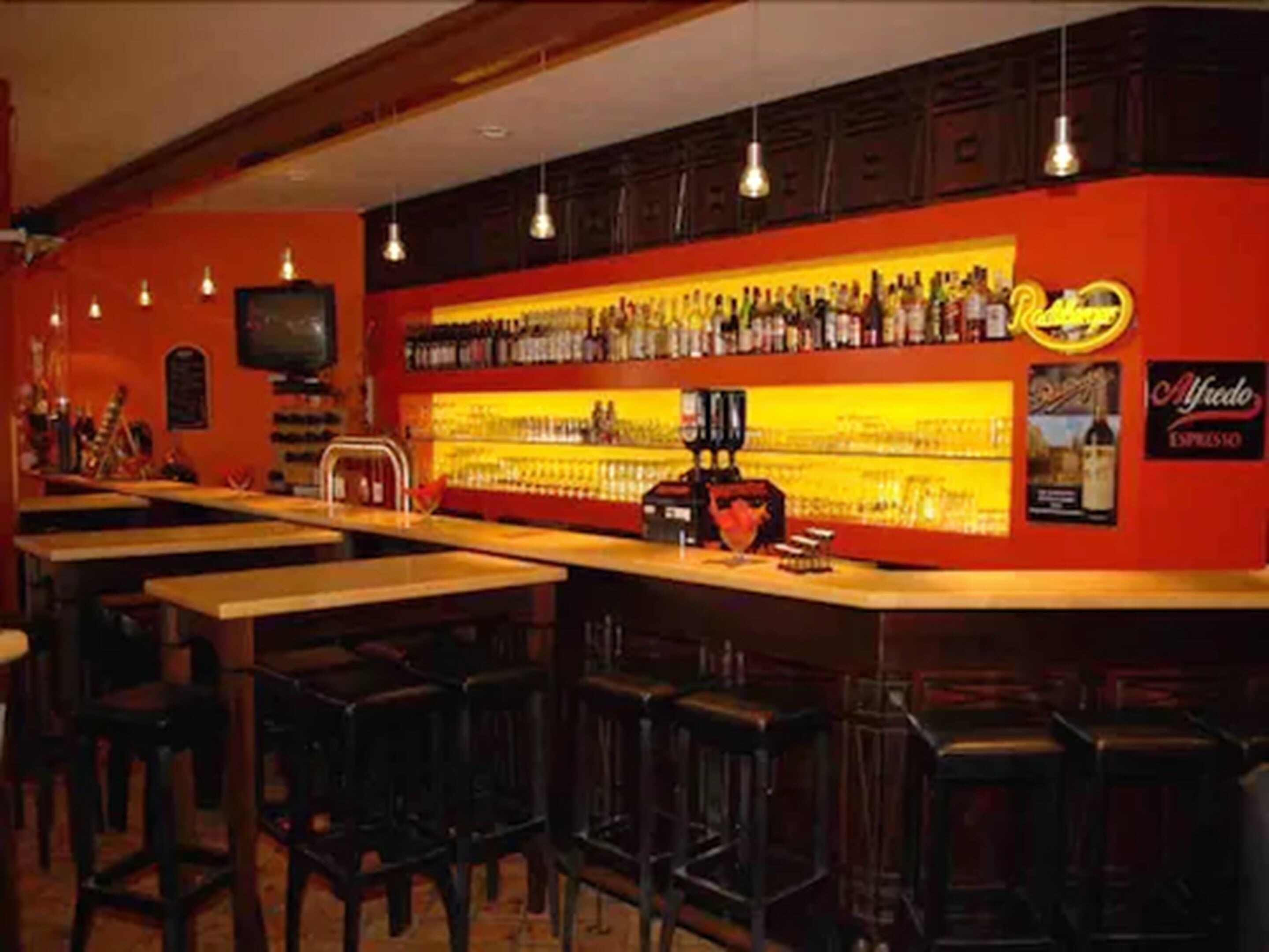 A bar area with multiple stools and a counter stocked with bottles.