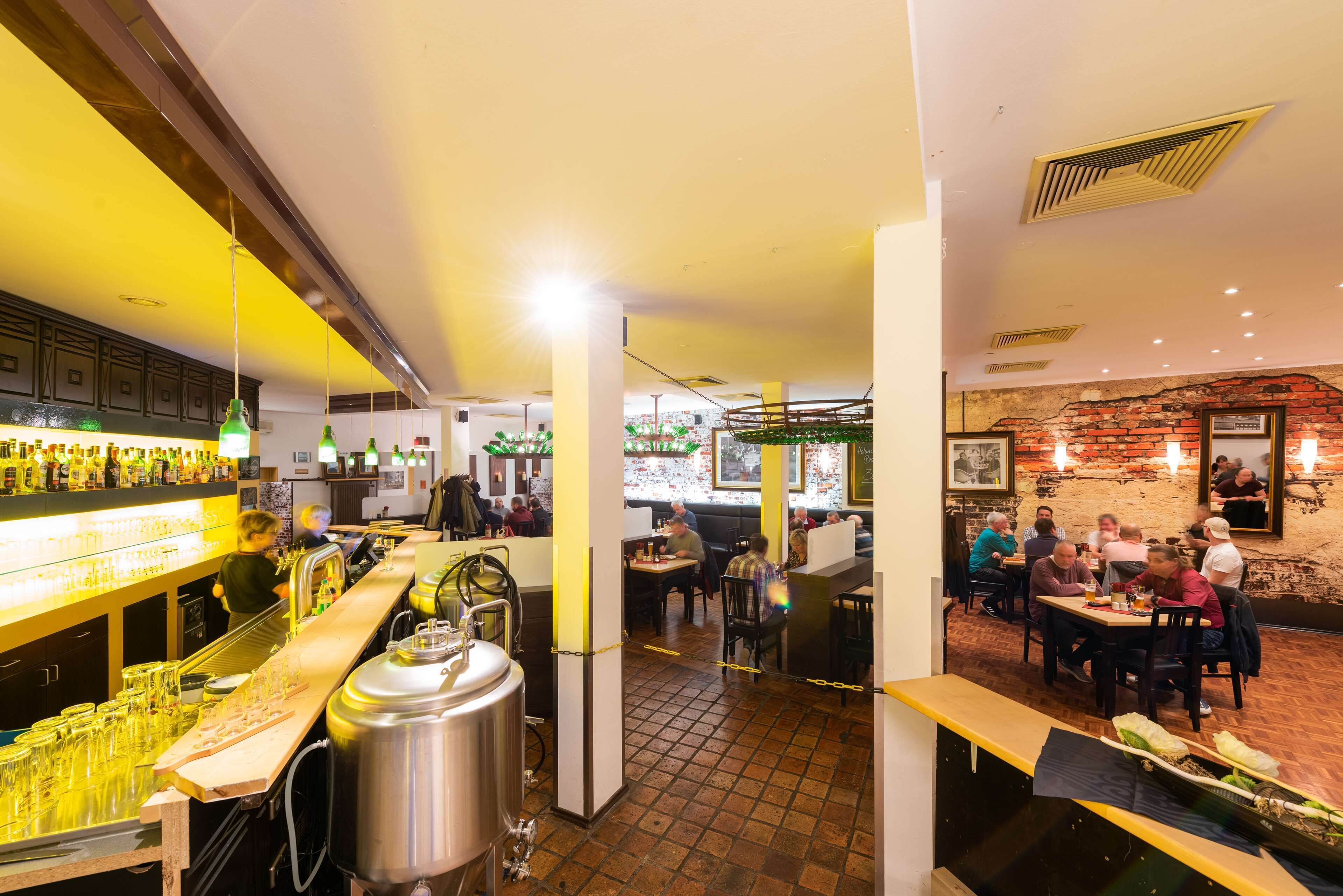 A restaurant with a bar area, tables, and chairs.
