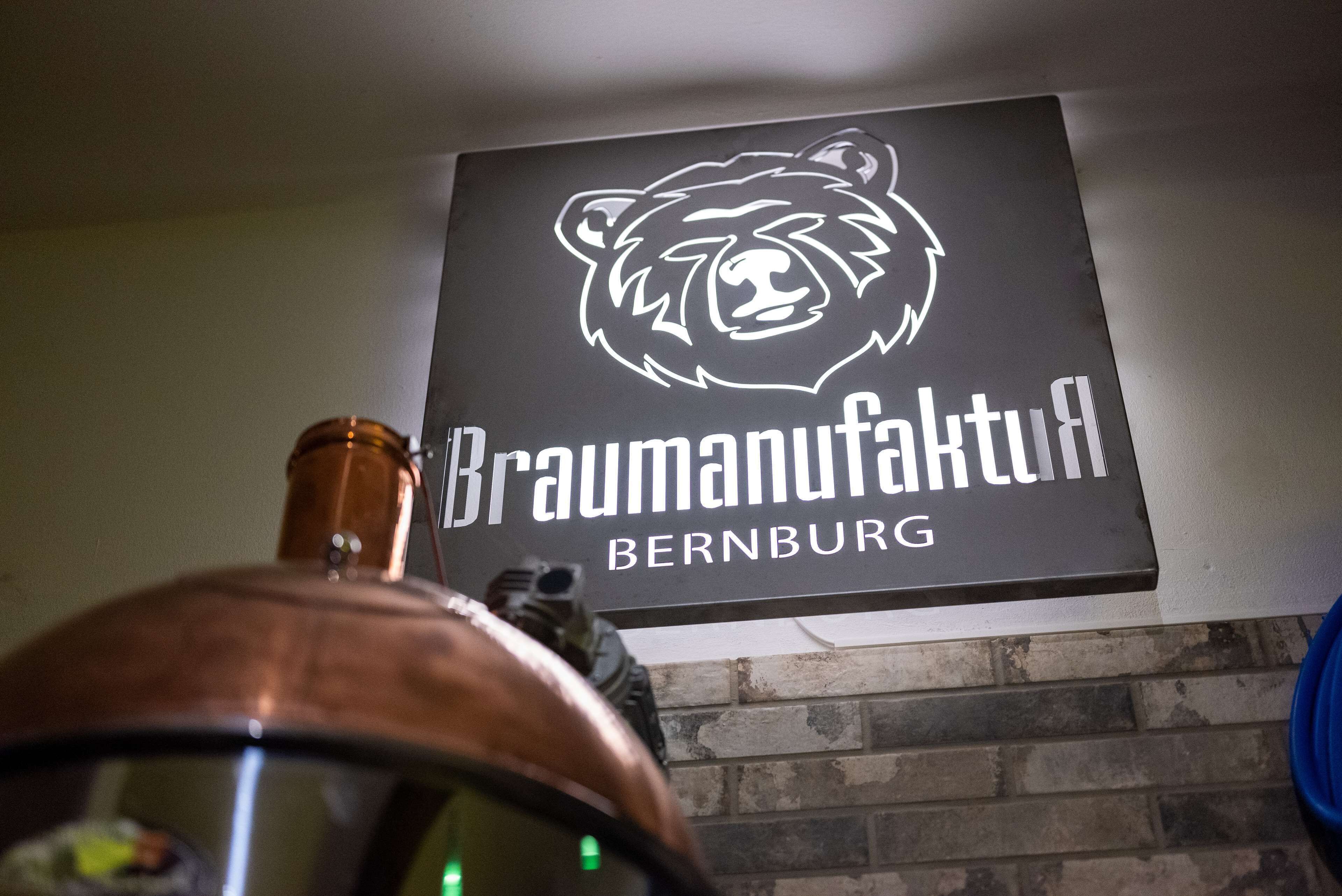 En skylt med en björnlogotyp och texten ”Braumannufactur BERNBURG” på en vägg.