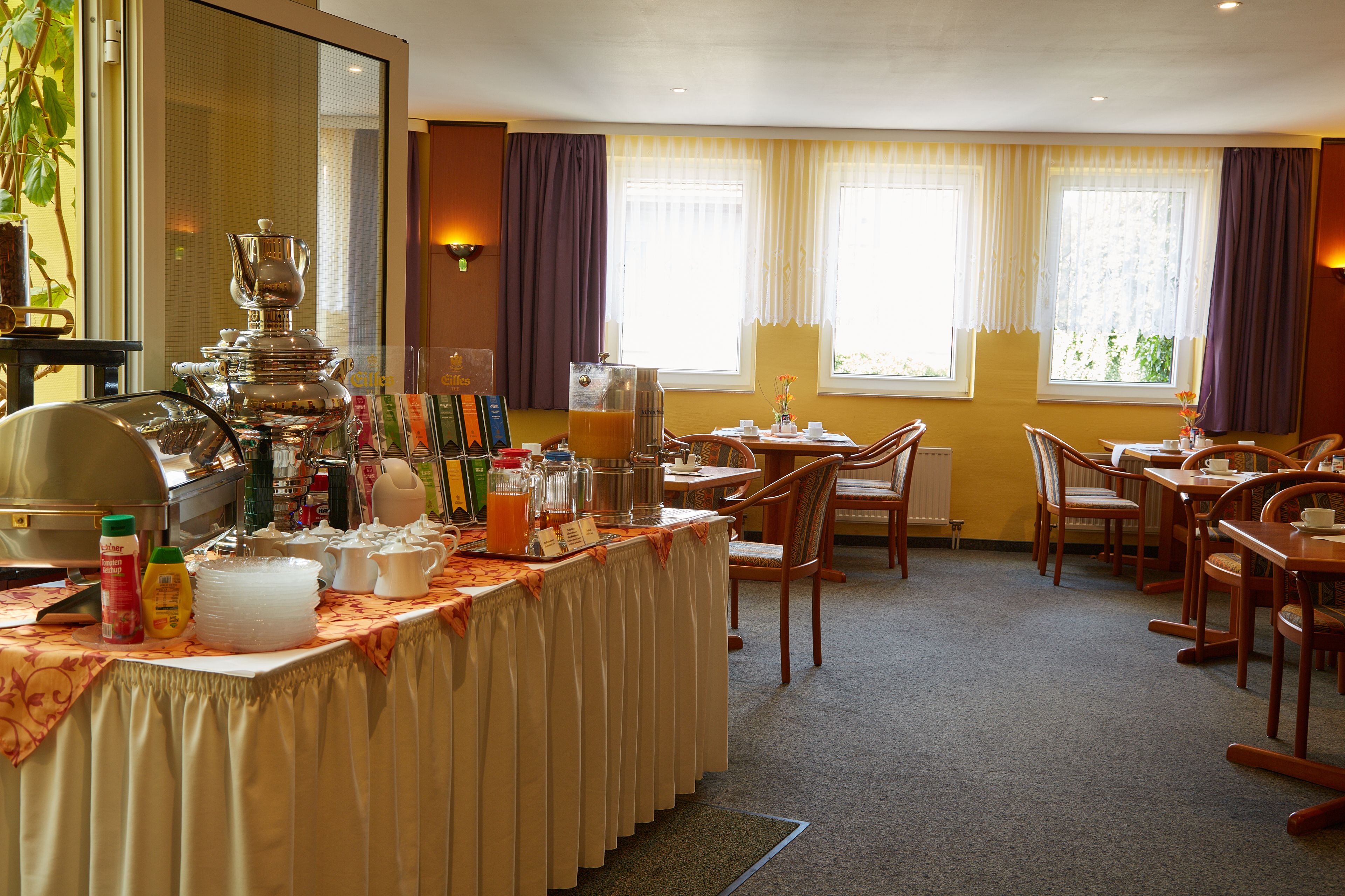 A hotel dining area with a buffet setup, including a variety of food items and a coffee station.