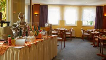 A hotel dining area with a buffet setup, including a variety of food items and a coffee station.