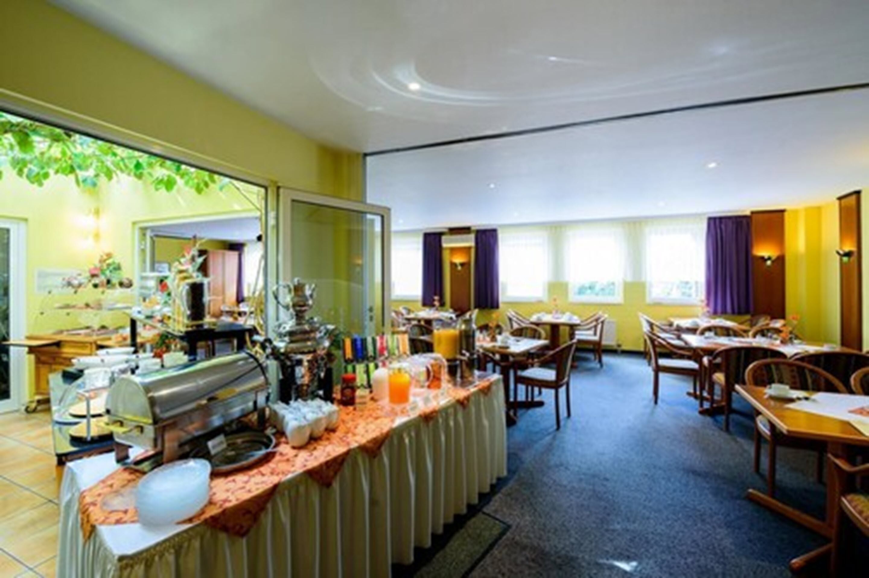 A breakfast buffet area with a variety of food items and a coffee station.