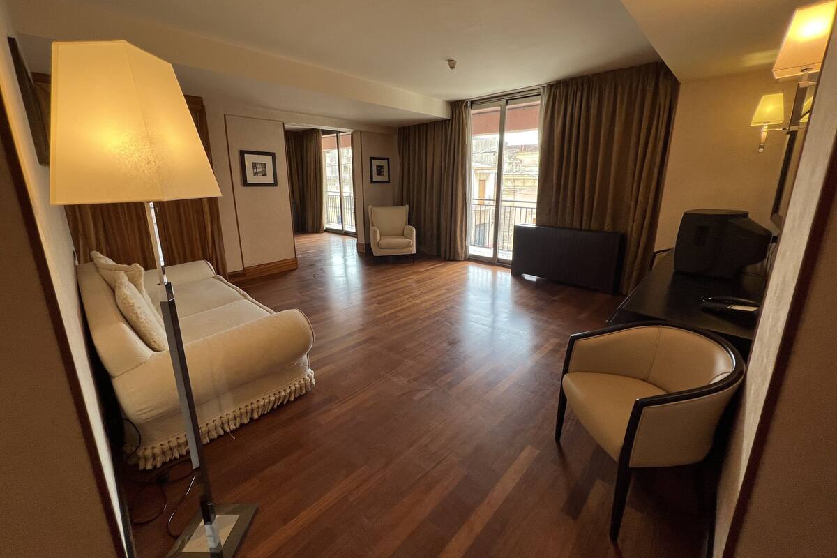 Une chambre d’hôtel avec un lit, un bureau, une chaise, une télévision et une lampe.