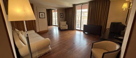 Una habitación de hotel con cama, escritorio, silla, televisor y lámpara.