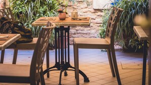 A brick wall with a lattice, potted plants, and a table with chairs in a courtyard. - Locanda Ca' Lucrezia (Venice)