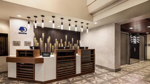 A reception desk with a modern design, featuring a logo and nameplate, and a patterned floor. - Manhattan Centre Hotel (New York)
