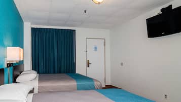 Una habitación de hotel con dos camas, un televisor montado en la pared, una puerta con cerradura y una lámpara en el techo.