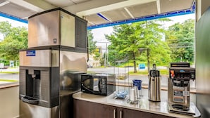 Un espace café en libre-service équipé d’un four à micro-ondes, d’une machine à café et d’un distributeur de boissons.