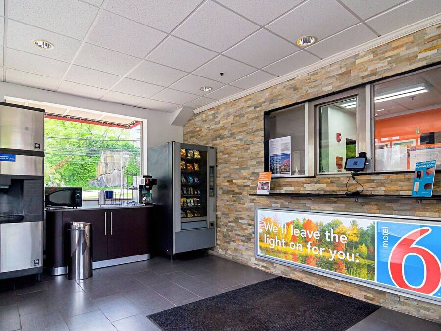 Un moderno vestíbulo de hotel con una pared de piedra, una máquina de café, un microondas y un cubo de basura.