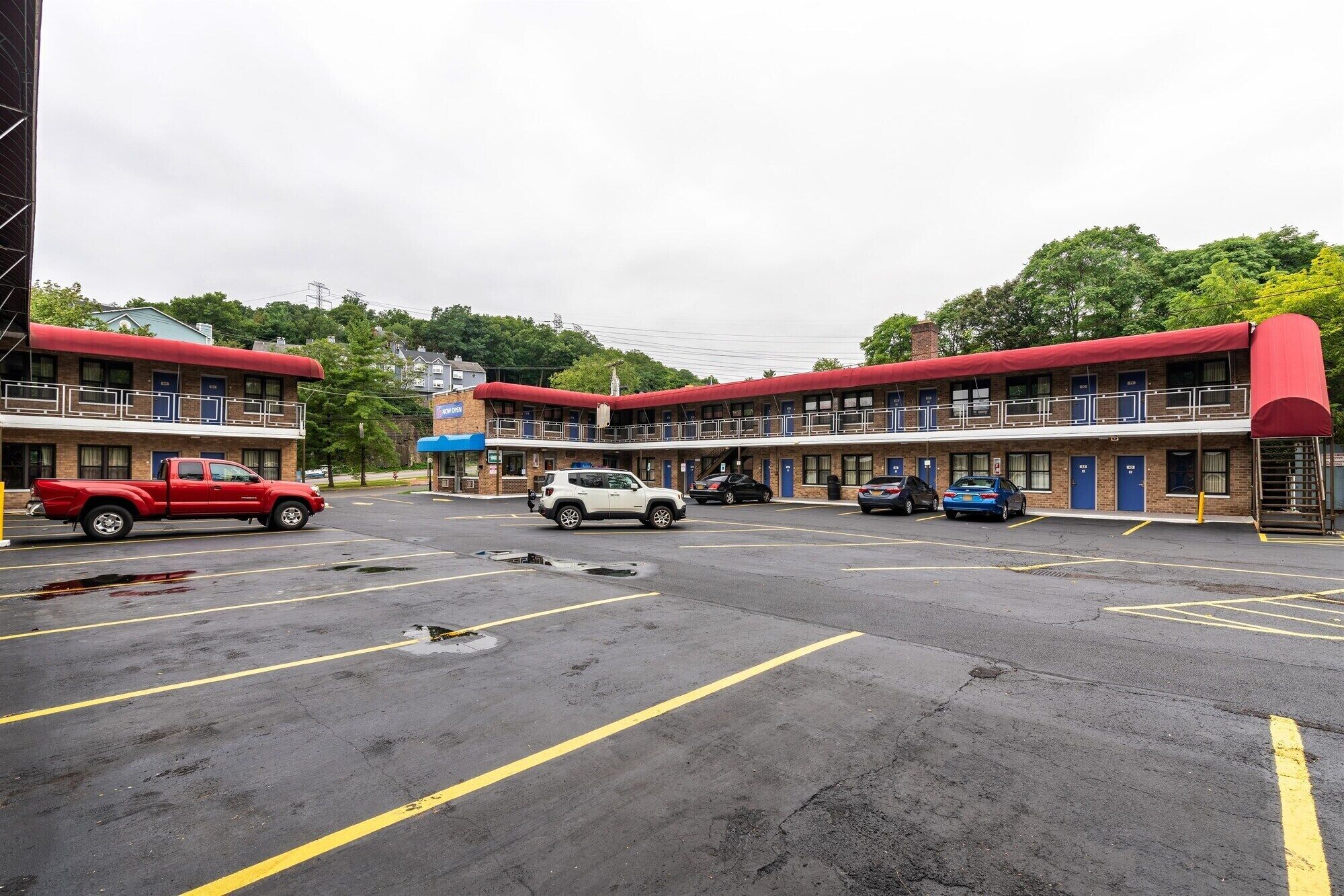 Un motel con varios edificios de dos pisos, un estacionamiento y varios automóviles aparcados.