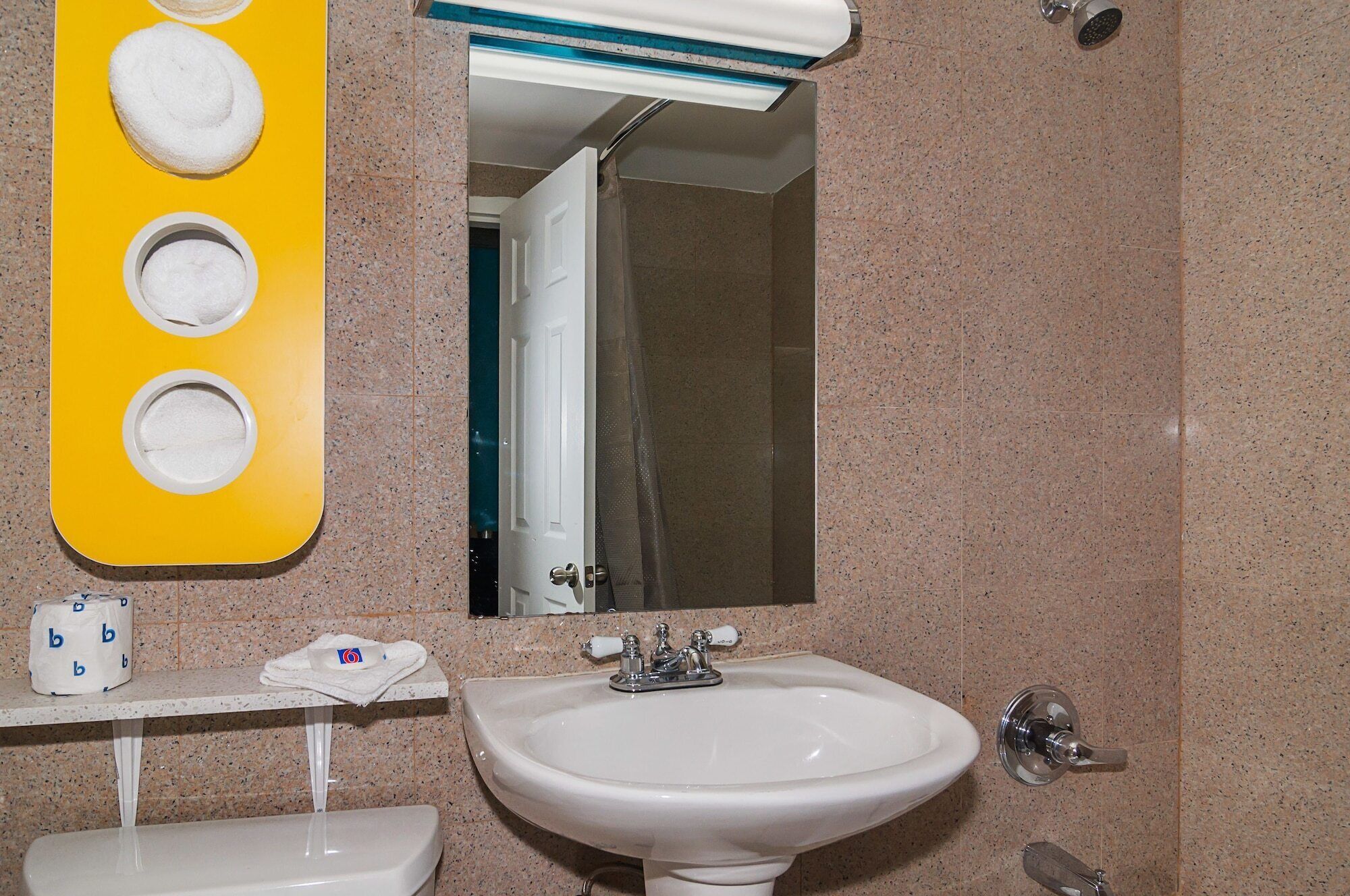 Un baño con un lavabo blanco, un espejo y un dispensador de toallas amarillo.