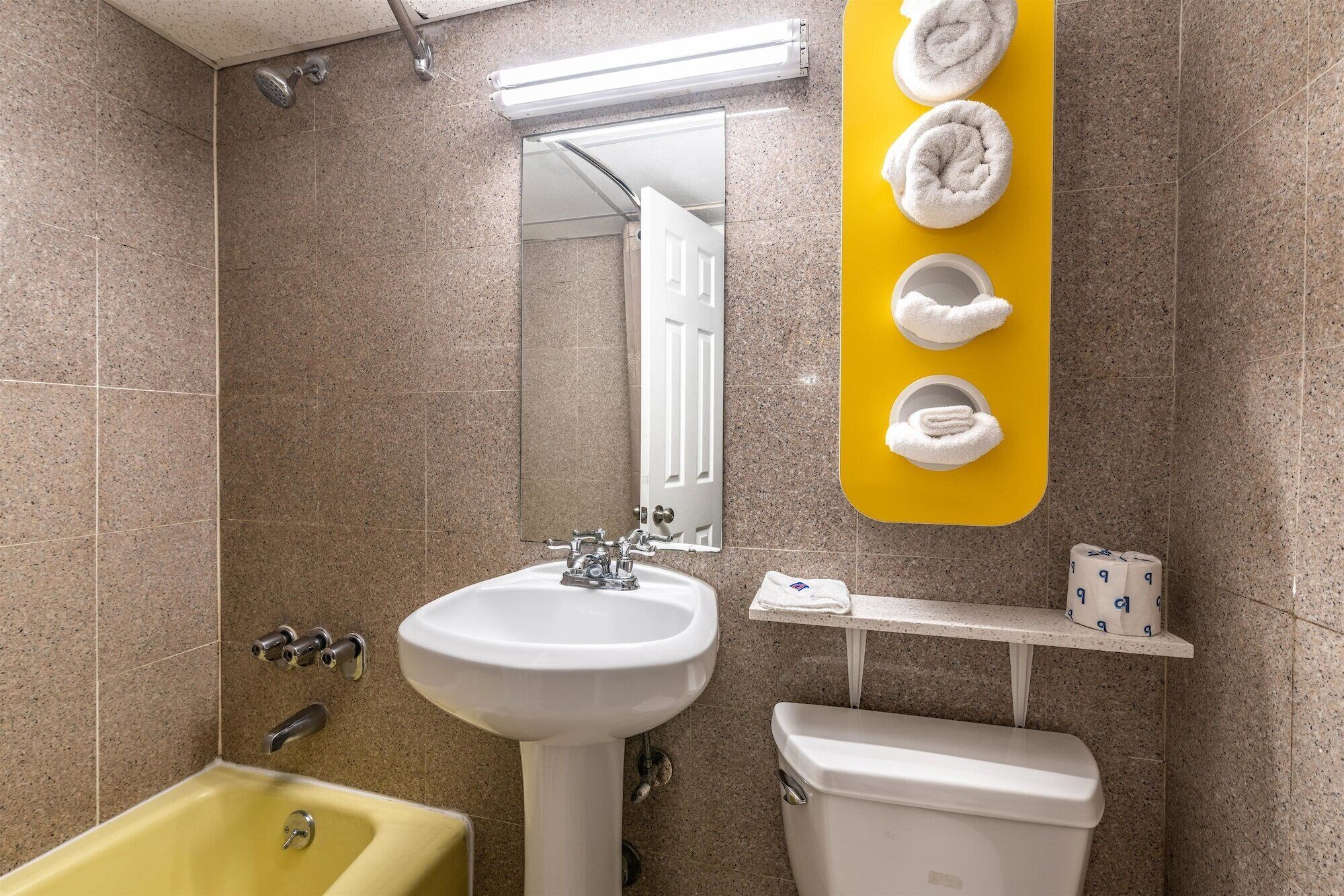 Un baño con toallero amarillo, lavabo, inodoro y bañera.