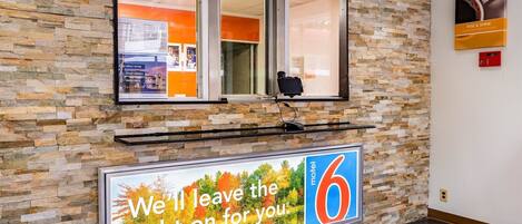 A reception area with a stone wall, a window, a signboard, and a security camera.