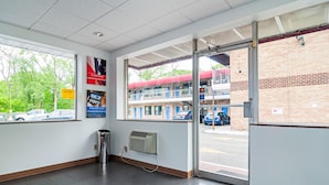 Un espace intérieur propre et bien éclairé, doté d’une grande fenêtre donnant sur un parking et un bâtiment avec un auvent rouge.