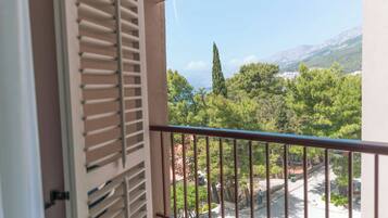 A balcony with a view of a mountainous landscape, trees, and a clear sky.