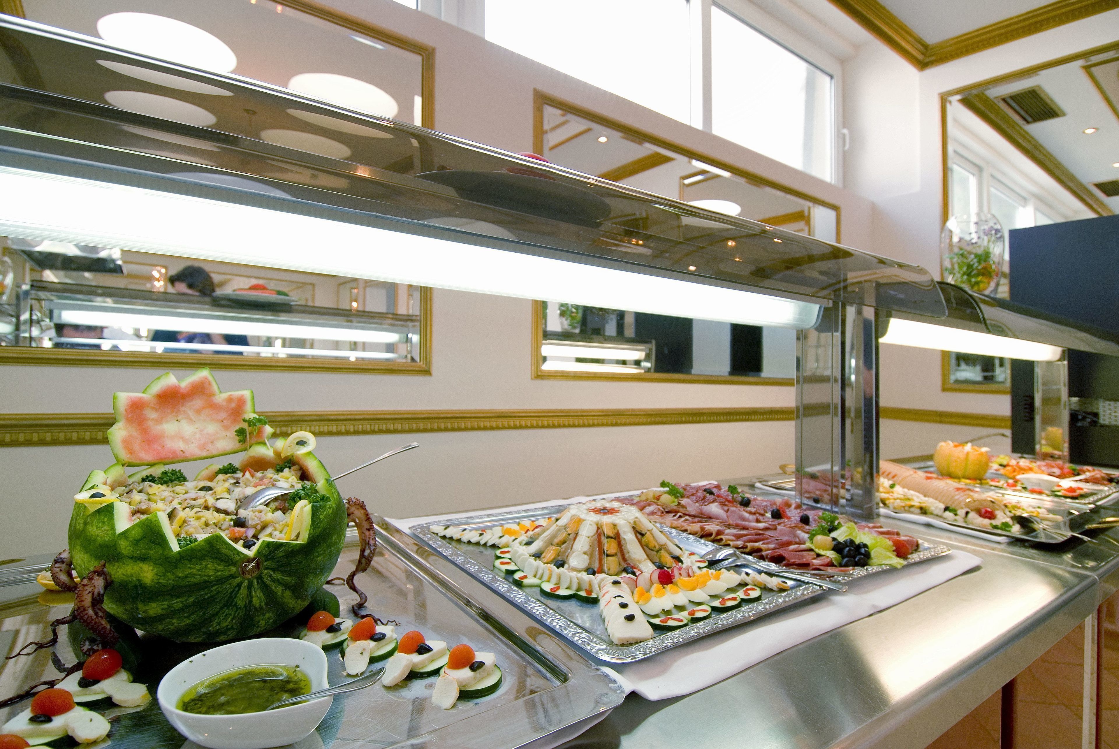 A buffet with various food items, including a watermelon bowl, trays of sandwiches, and a bowl of green sauce.