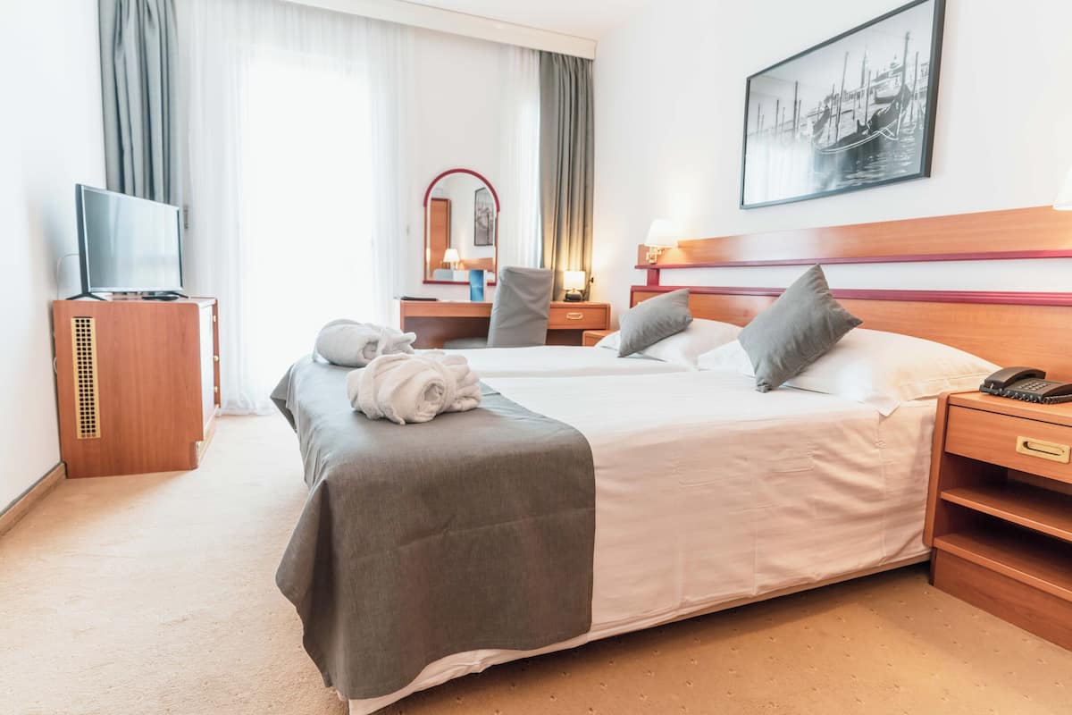 A hotel room with a large bed, a TV, a desk, and a mirror.