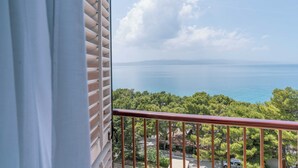 Ein Balkon mit Blick auf eine Küstenlandschaft, Bäume und das Meer.