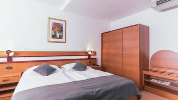A neatly arranged hotel room with a bed, bedside tables, a wardrobe, and a framed picture on the wall.