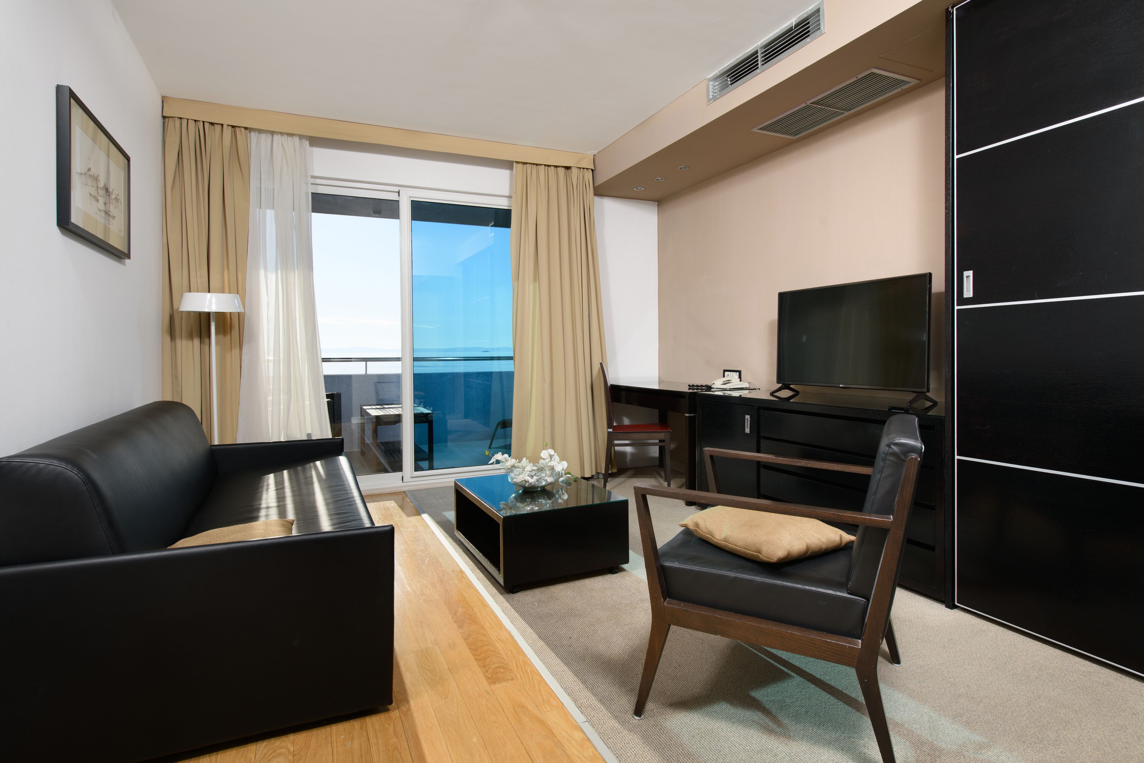Une chambre d’hôtel moderne équipée d’un canapé, d’un fauteuil, d’une table basse et d’un téléviseur.