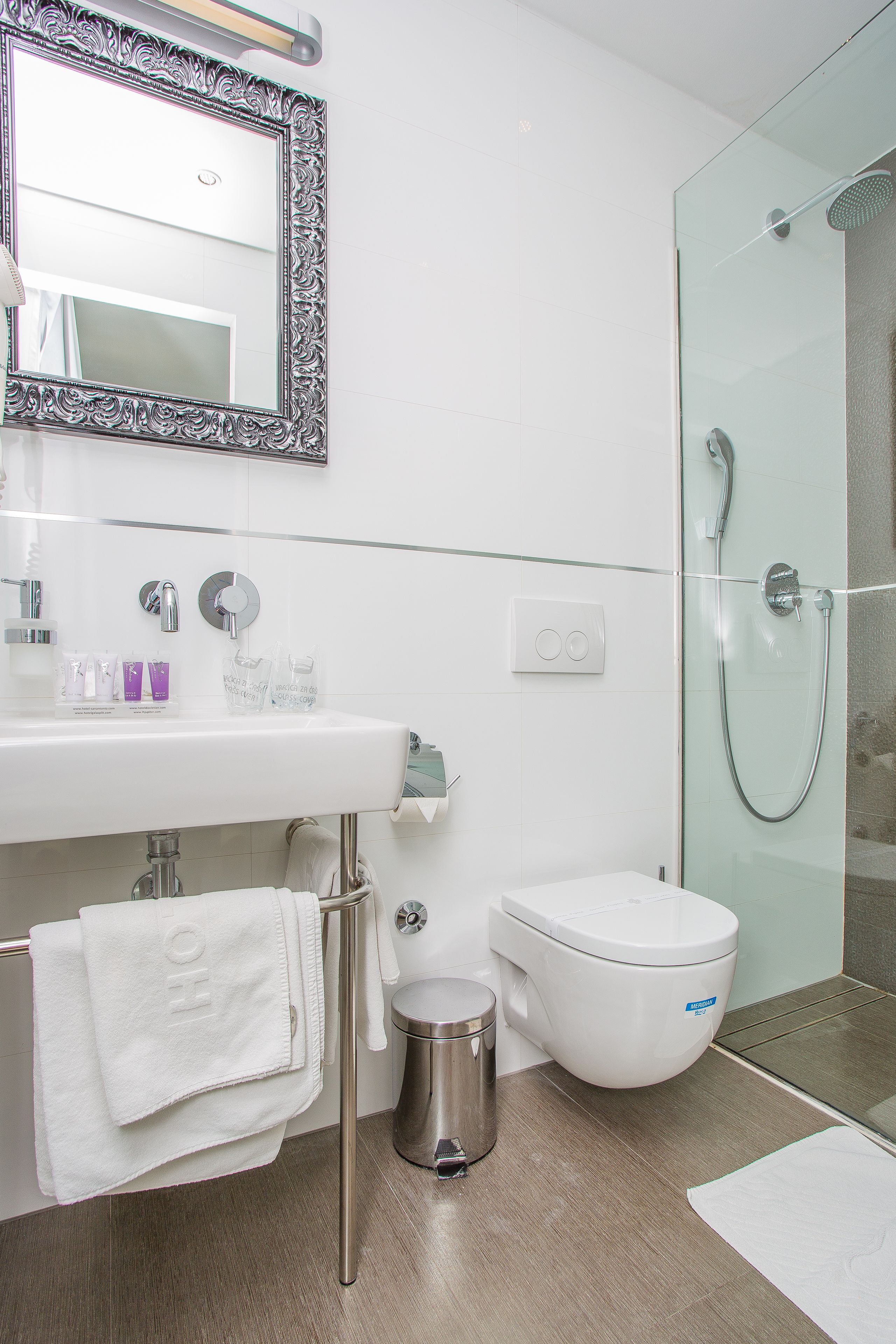A modern bathroom with a white sink, mirror, toilet, and glass shower enclosure.