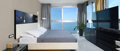 Habitació d'hotel moderna amb un llit gran, televisió, escriptori i vistes al mar.