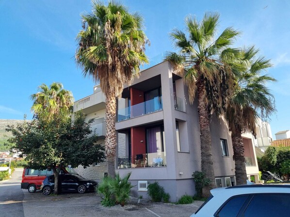 Un edificio moderno de dos pisos con balcones, rodeado de palmeras.