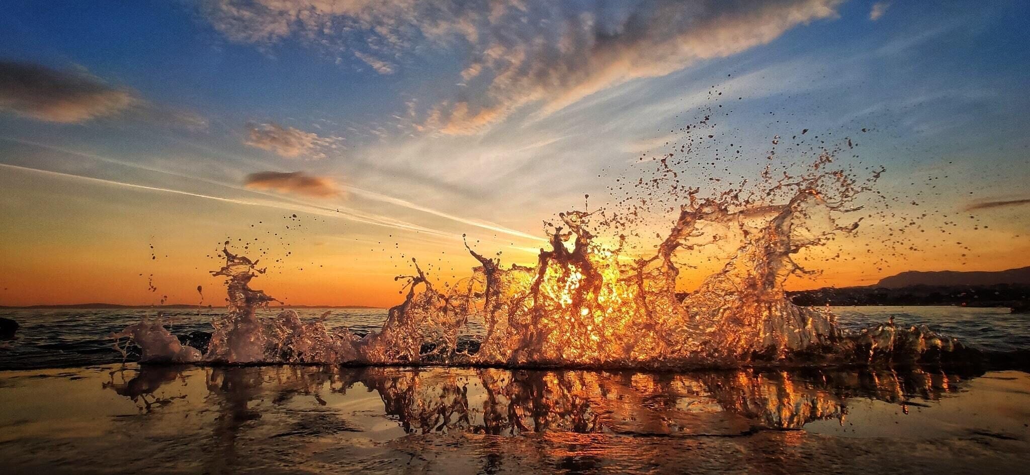 A sunset over water with splashes reflecting on the surface.