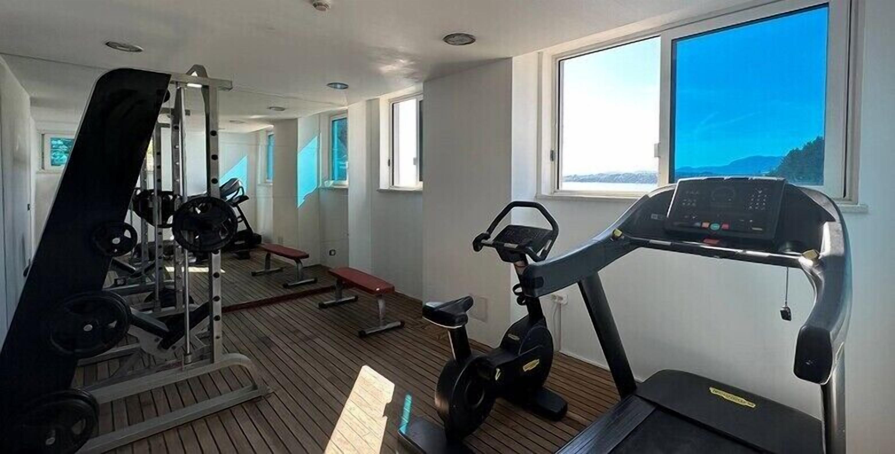 Un gimnasio con equipo de ejercicio, una cinta de correr y un banco.