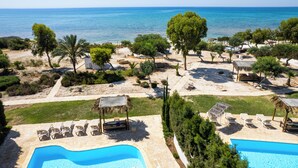 A resort with a swimming pool, sun loungers, and a view of the sea. - Thalassines Beach Villas (Sotira)