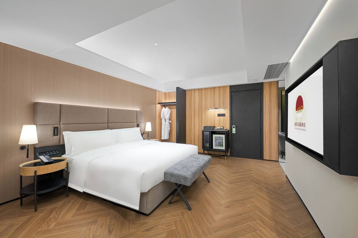 Una habitación de hotel moderna con una cama grande, mesitas de noche, un escritorio y un televisor.