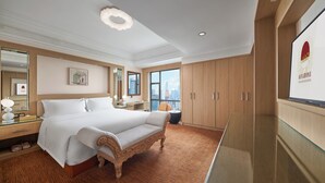 Habitación de hotel con una cama grande, un armario de madera, una mesa de vidrio y vistas a la ciudad.