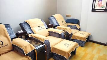Relax in comfort with four massage therapy beds, each covered in a plush blanket, surrounded by soothing artwork and a clock.