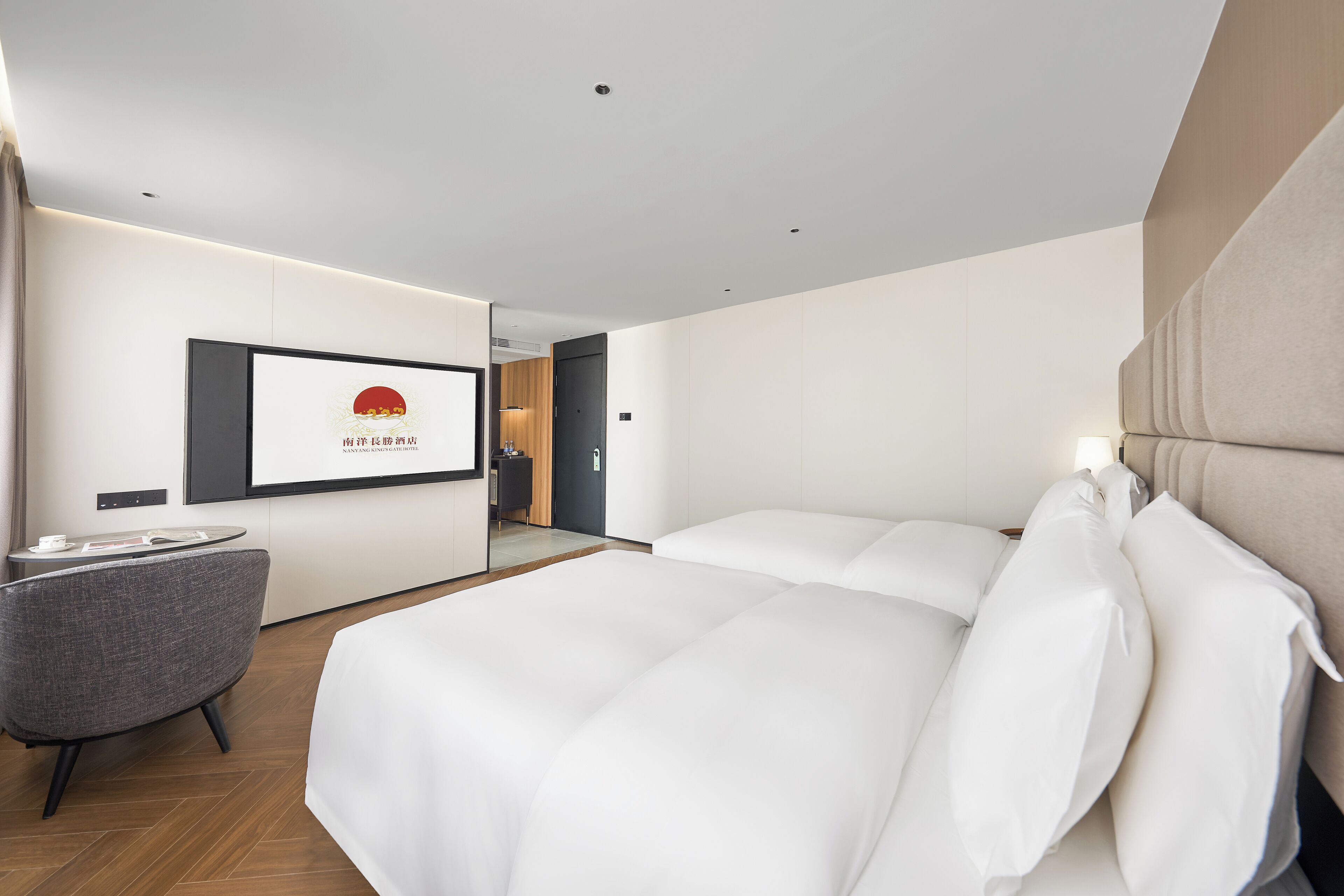 Ein modernes Hotelzimmer mit einem großen Bett, einer kleinen Sitzecke und einem an der Wand befestigten Fernseher.