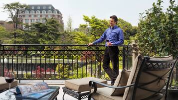 A man standing on a balcony with a view of a building and greenery.