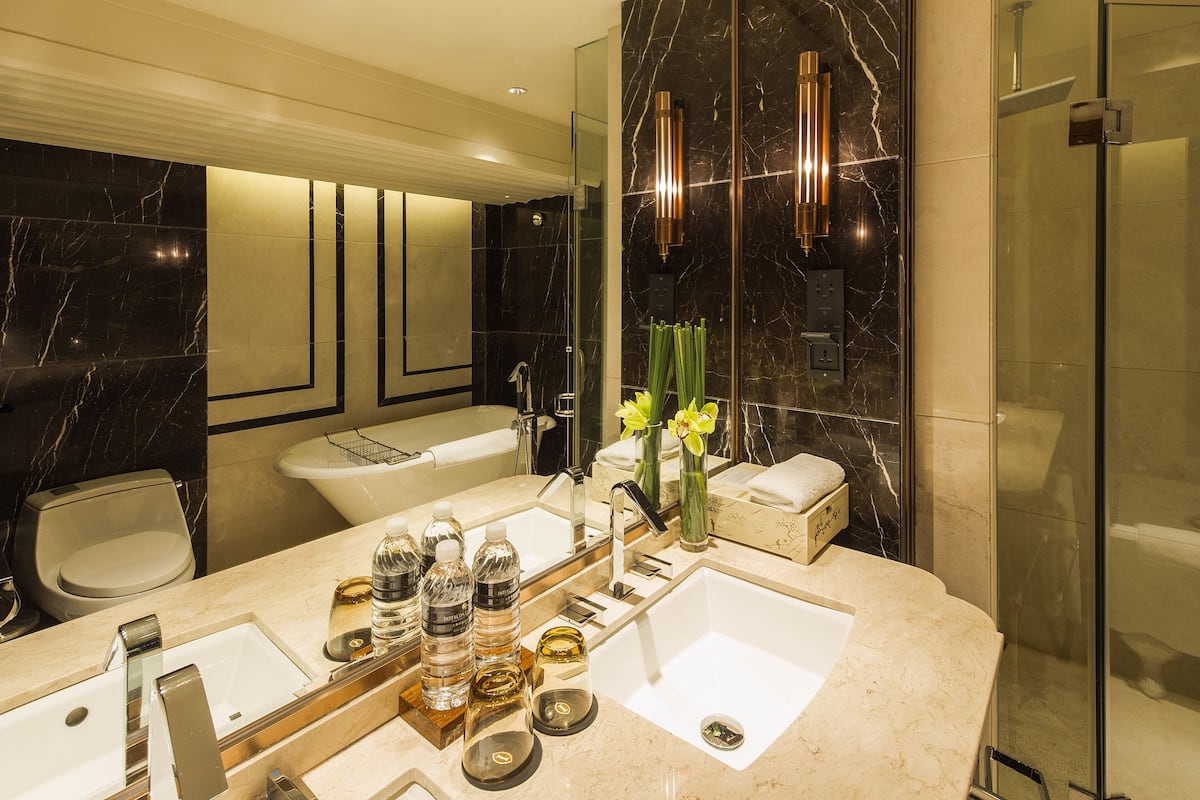 A modern bathroom with a large vanity, dual sinks, a bathtub, and a glass shower enclosure.