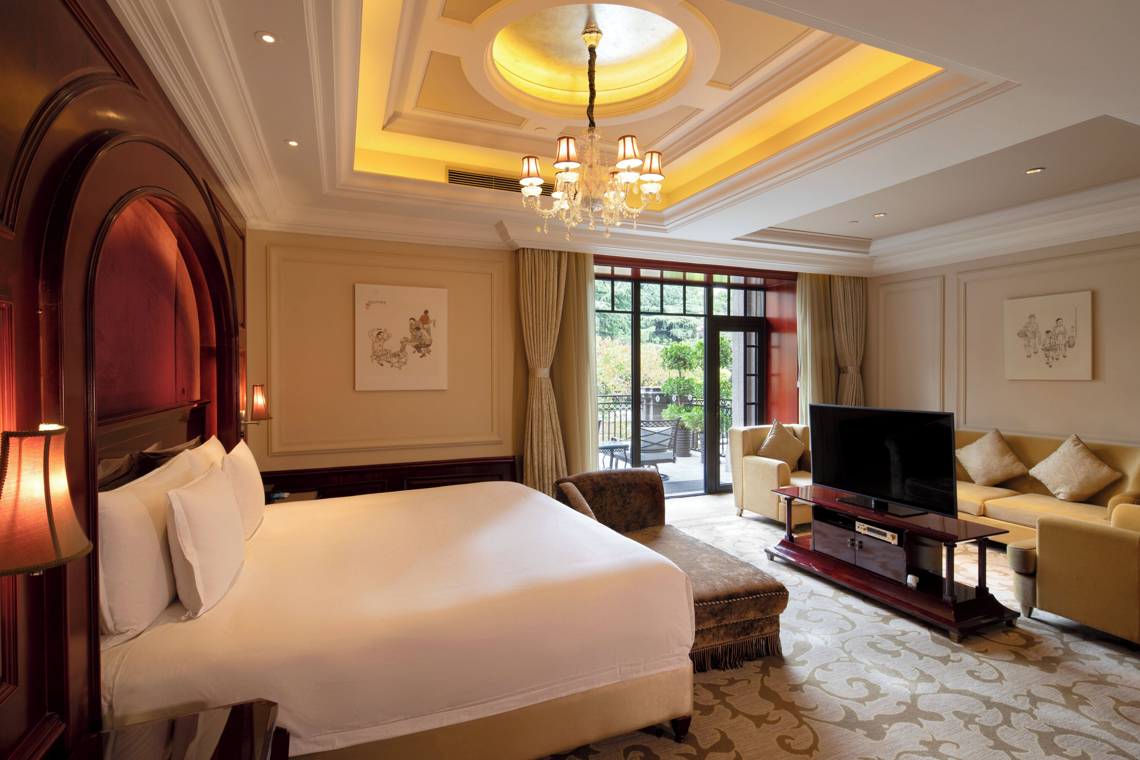 Habitación de hotel con una cama grande, televisor, sofá y zona de comedor con vistas.