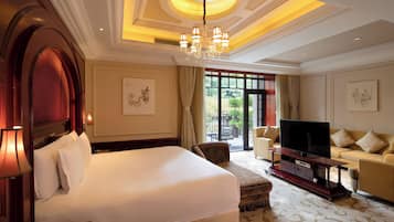 Habitación de hotel con una cama grande, televisor, sofá y zona de comedor con vistas.