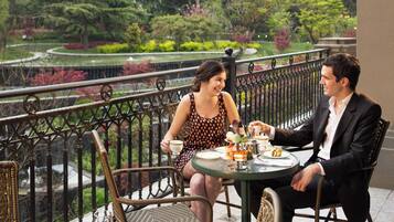 Una pareja sentada a una mesa con vista a un jardín, disfrutando de un servicio de té.
