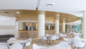 A modern hotel lobby with round tables and white chairs, a bar area, and a large plant. -  Hotel Rosamar Benidorm (Benidorm)