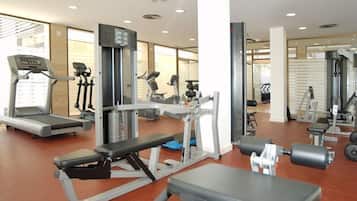 Un gimnasio con cintas de correr, máquinas de pesas y pesas sueltas.