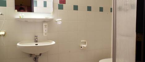 Un baño con lavabo, espejo e inodoro.