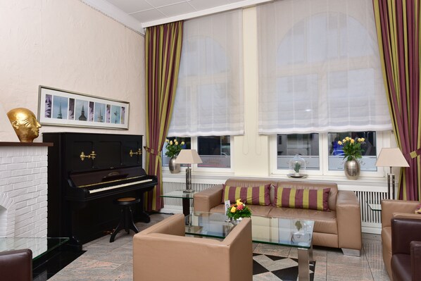 Una sala de estar con un piano, un sofá, una mesa de centro de vidrio y una chimenea.