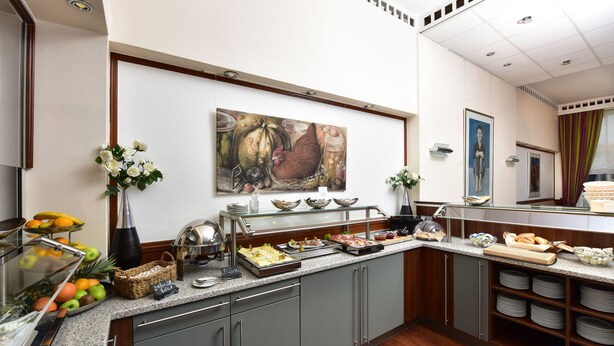 Una mesa de buffet con diferentes opciones de comida, un cuadro en la pared y un florero con flores.