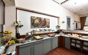 Una mesa de buffet con diferentes opciones de comida, un cuadro en la pared y un florero con flores.