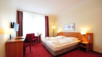 Une chambre d’hôtel avec deux lits, un bureau avec un ordinateur, une chaise, une petite table et un téléviseur.