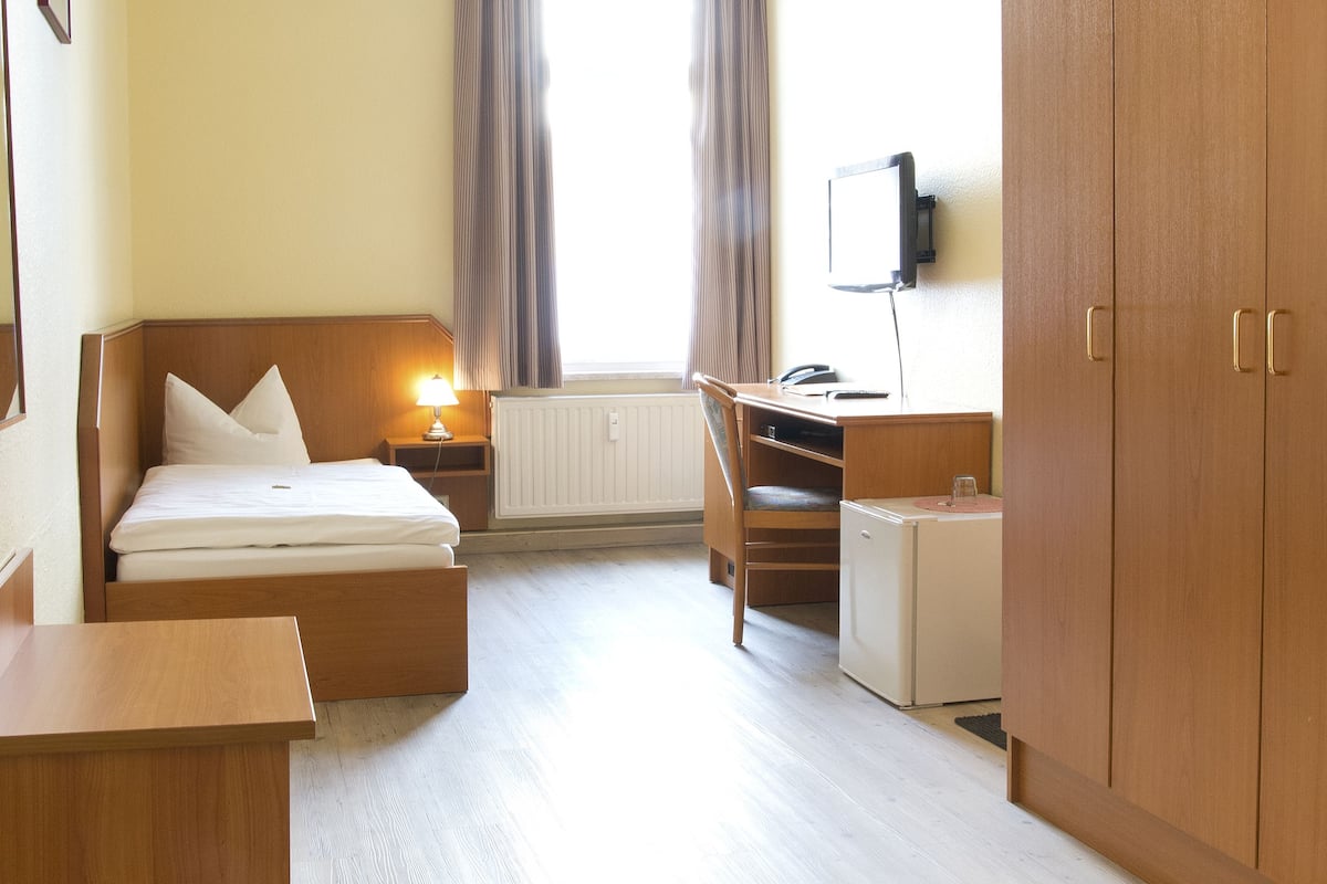 Habitación de hotel con cama, escritorio y armario.